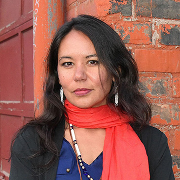 Photo of Dr. Michelle Johnson-Jennings standing against a brick wall